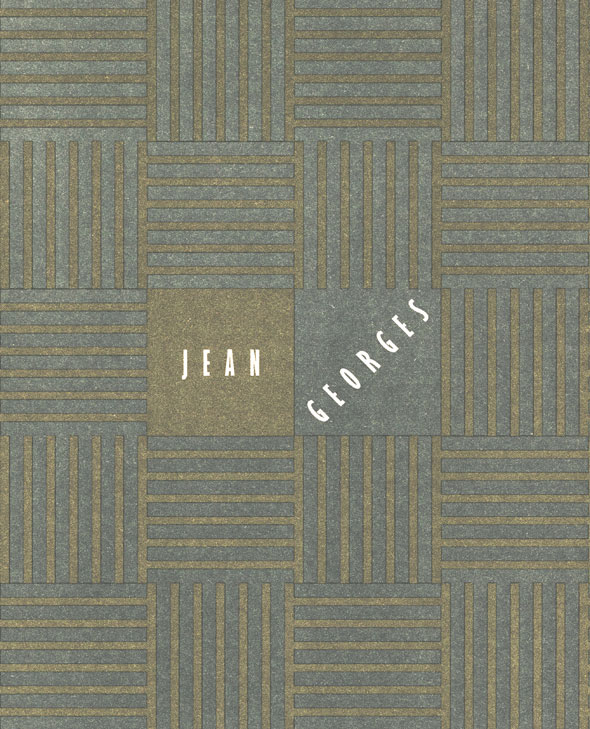 A olive green and blue-grey menu. The menu has a olive green background and has a pattern of horizontal and vertical blue-grey striped squares throughout the menu. In the middle is two squares, on the left is plain olive green and on the right, next to it, is a plain blue-grey square. In the olive green square is "Jean" in all capital white letters in a narrow bolded text. In the blue-grey square is "Georges" in all capital white letters in a narrow bolded text. "Georges", however, is not vertical but rather diagonal in the square.