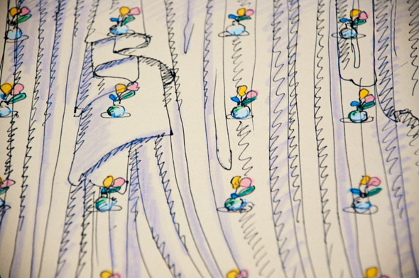 A close up of a rough sketch of a light purple curtain with folds. The curtain has several designs of a tiny blue glass vase with two yellow and pink flowers.
