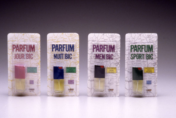 A photo of 4 packages of tiny perfume bottles. All packages has a white background with black outlines of a map with the perfume on the bottom right. Above the perfume is thin bold text reads the perfume's name, each package has a different color