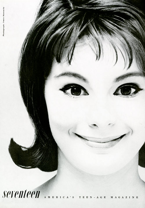 Black and white photo of a young woman with a flip hairstyle smiling into the camera