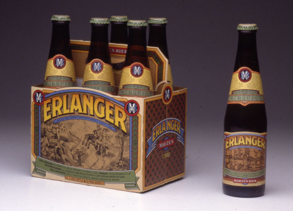 A photo of a 6-pack carton of beer bottles. One of the bottle is taken out and placed next to the 6-pack. The design of the beer carton has the name of the brand, "Erlanger" very big and at an arch. Each letter has a gradient of orange to yellow. Underneath the name is an illustration of a an old fashion couple near a forestry trail. The design of the beer bottle has the name design for the brand name on it's label. With an illustration underneath it. 