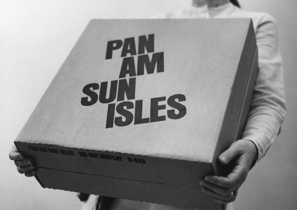 Close up of a case being carried by somebody; text is printed on it reading 'Pan Am Sun Isles'