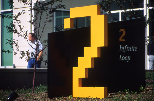 A pixelated, yellow-orange "2" typography displayed outside a building entrance. Titled "Infinite Loop".
