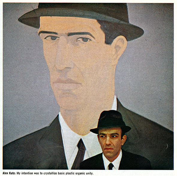 Photo of Alex Katz posing with his self-portrait illustrated on the wall behind him.