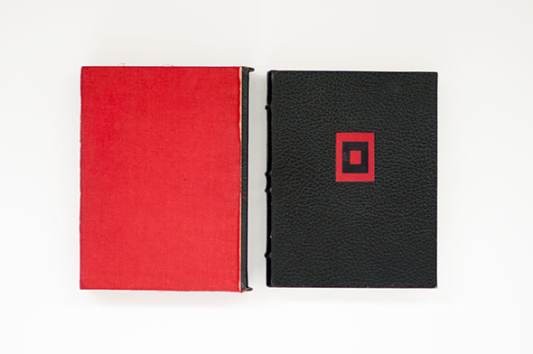 Book slipcover, red with a black spine. The book on the right is black with a small red square within red rectangle design.