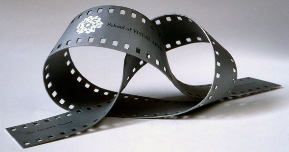 A photo of a film strip shaped into a pretzel form. At one end "The DUSTY Award" is printed in black text. In the middle of the film strip is the the School of Visual Art's logo with " School of VISUAL ARTS" printed in black text. 