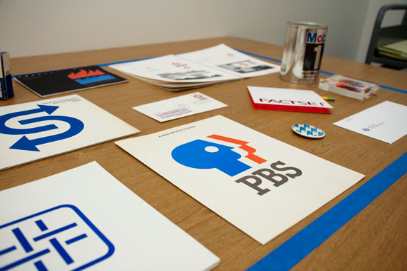 A photo of a working table with a variety of logos displayed.