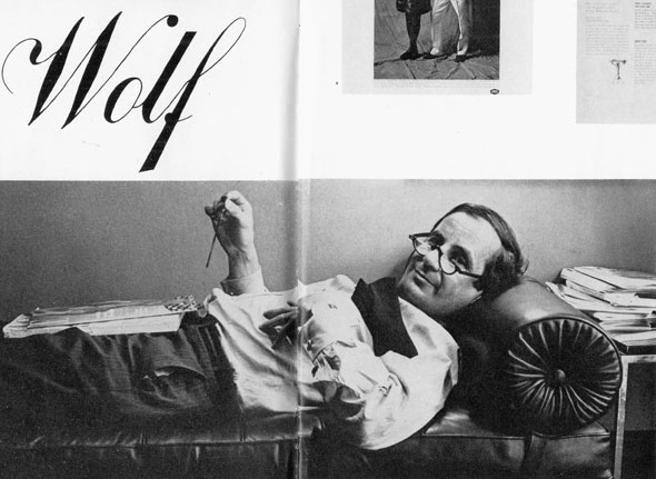 Black and white photo of Henry Wolf reclining on the Mies-style couch in the vice president’s office.
