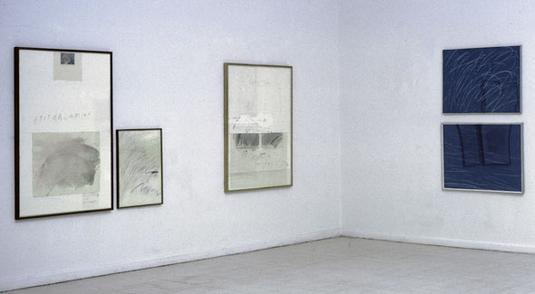 Color photo of the interior corner of an art gallery, displaying four paintings