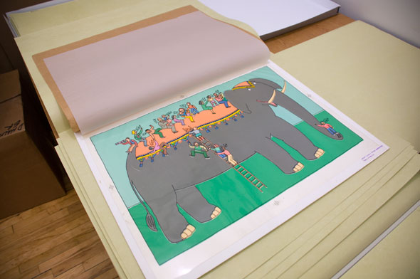 A photo of the elephant illustration. The outline drawing cel is laid on top of the coloring paper and it forms into one piece. The coloring are bright, with neon light orange decorations on the grey elephant, that is walking in a green field. The crowd of people wear all colorful different clothing. 