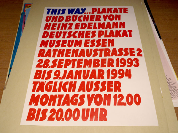 Poster for Edelmann exhibition depicting red and blue block text against white background.