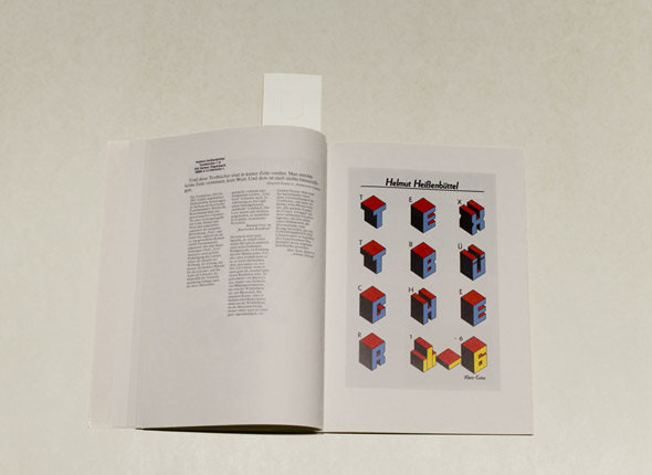 Book spread on white table; grid of colorful three-dimensional letters