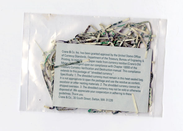 Color photo of a clear plastic bag; shredded paper and a card with text are visible inside