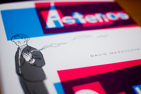 Photo of a book cover; Cartoon drawing of an older man smoking against a white background; Title text is white with overlapping pink and blue panels