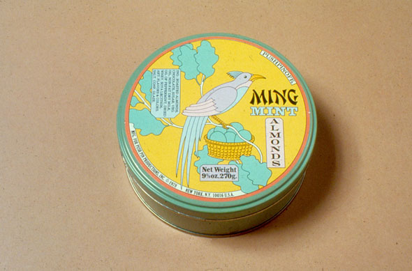Mint Almond tin; cover is a blue bird perched atop a clutch of eggs in a tree against a yellow sky