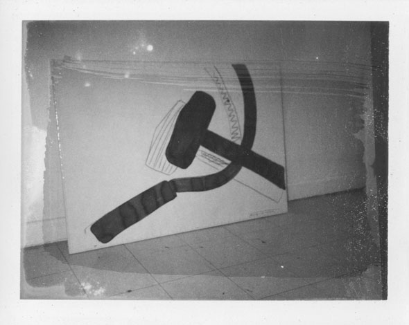A photo of a a huge canvas of a different version of the drawing of the mallet and the sickle. The drawing is much similar to the previous ones but is far less detailed. The photo is as a thick smear going across the photo causing that area to be slightly darker.