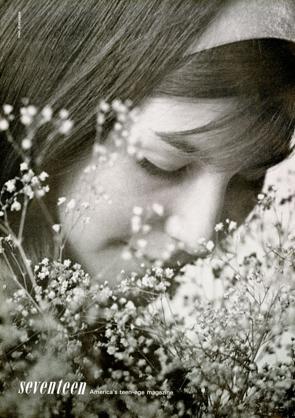 Closeup black and white photo of a long haired girl smelling baby's breath flowers