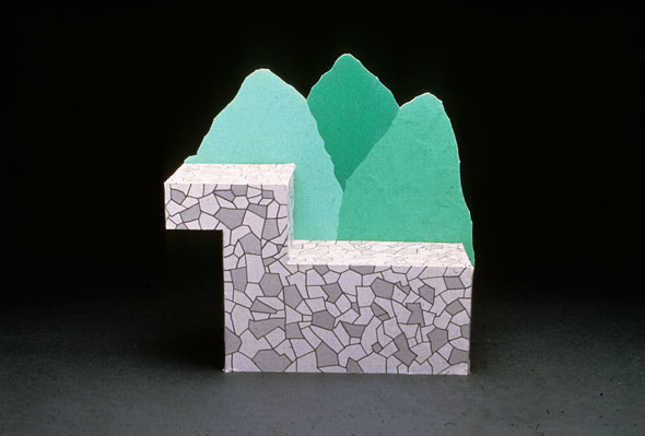 Photograph of a lounge seat on two levels, resembling rock, with stylized green trees as back support
