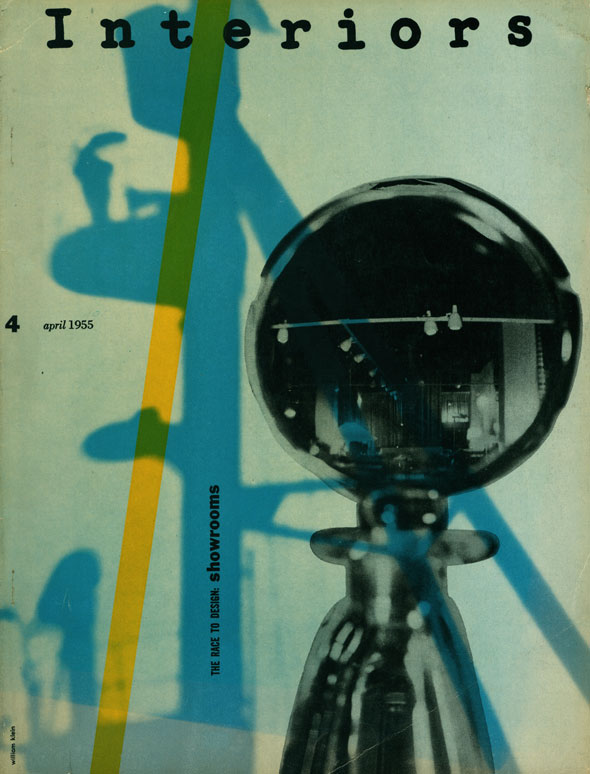 A furniture showroom reflected in the glass stopper of a bottle against a background of abstract blue and yellow shadows.