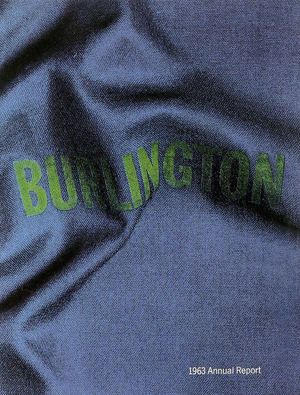 A photo of a dark blue denim fabric. "Burlington" in sewn into the fabric with bright green bold lettering. The fabric has a few folds that cause the lettering to curve. On the bottom of the photo in white text "1963 Annual Report".