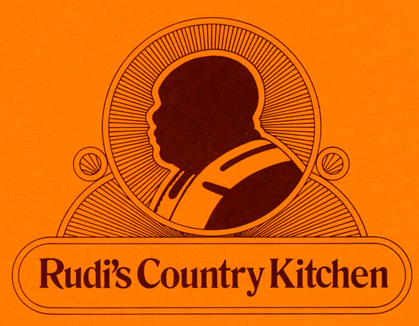 A brunt orange menu. In the middle is a dark brown silhouette of a black bald man in a pastor like clothing. The silhouette is in circle that has lines going inward towards the silhouette, giving is a holy-like glow. Underneath is "Rudi's Country Kitchen" in a dark dark formal lettering. The text is within a minimalistic boarder.