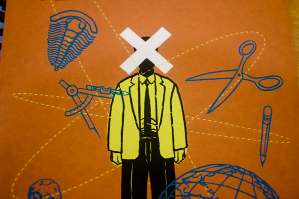 Simple drawing of a person in black pants and a yellow jacket with a large white X over their face, surrounded by a fossil, compass, pencil, globe, scissors.